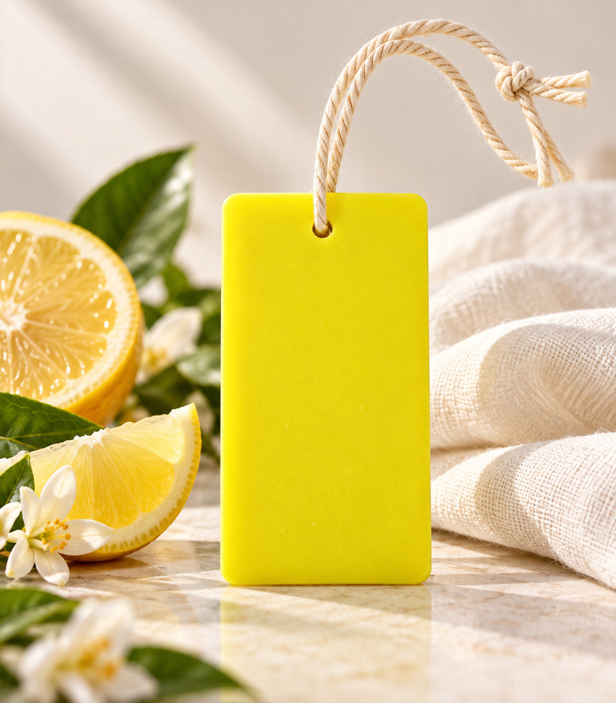 Pairsense Citrus aroma tag, a bright yellow tag on a cotton cord, beside cut lemons and lemon blossom