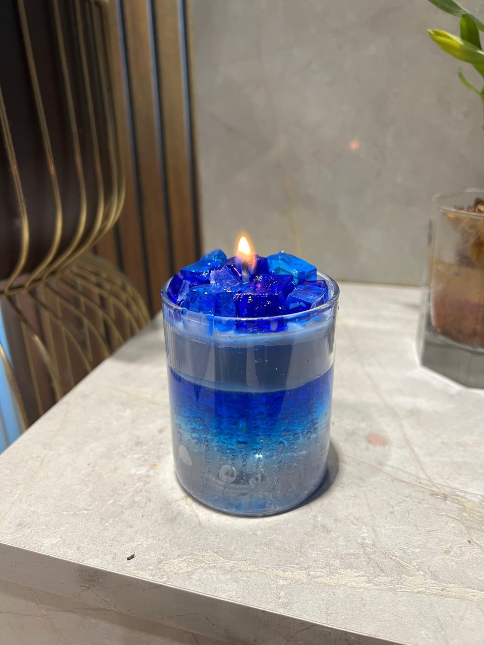 A customer's Pairsense Blue Crystal candle, blue crystals over layered blue gel, lit on a marble shelf