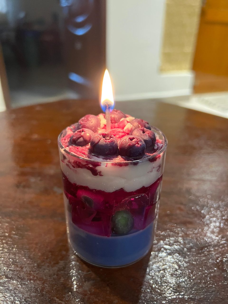A customer's Pairsense Blueberry candle, blueberries over cream and berry gel, lit on a wooden table