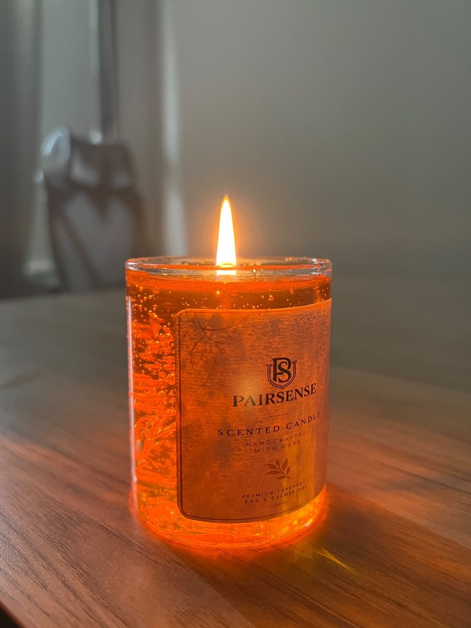 A customer's Pairsense Honey gel candle, lit on a wooden table, held outdoors and glowing