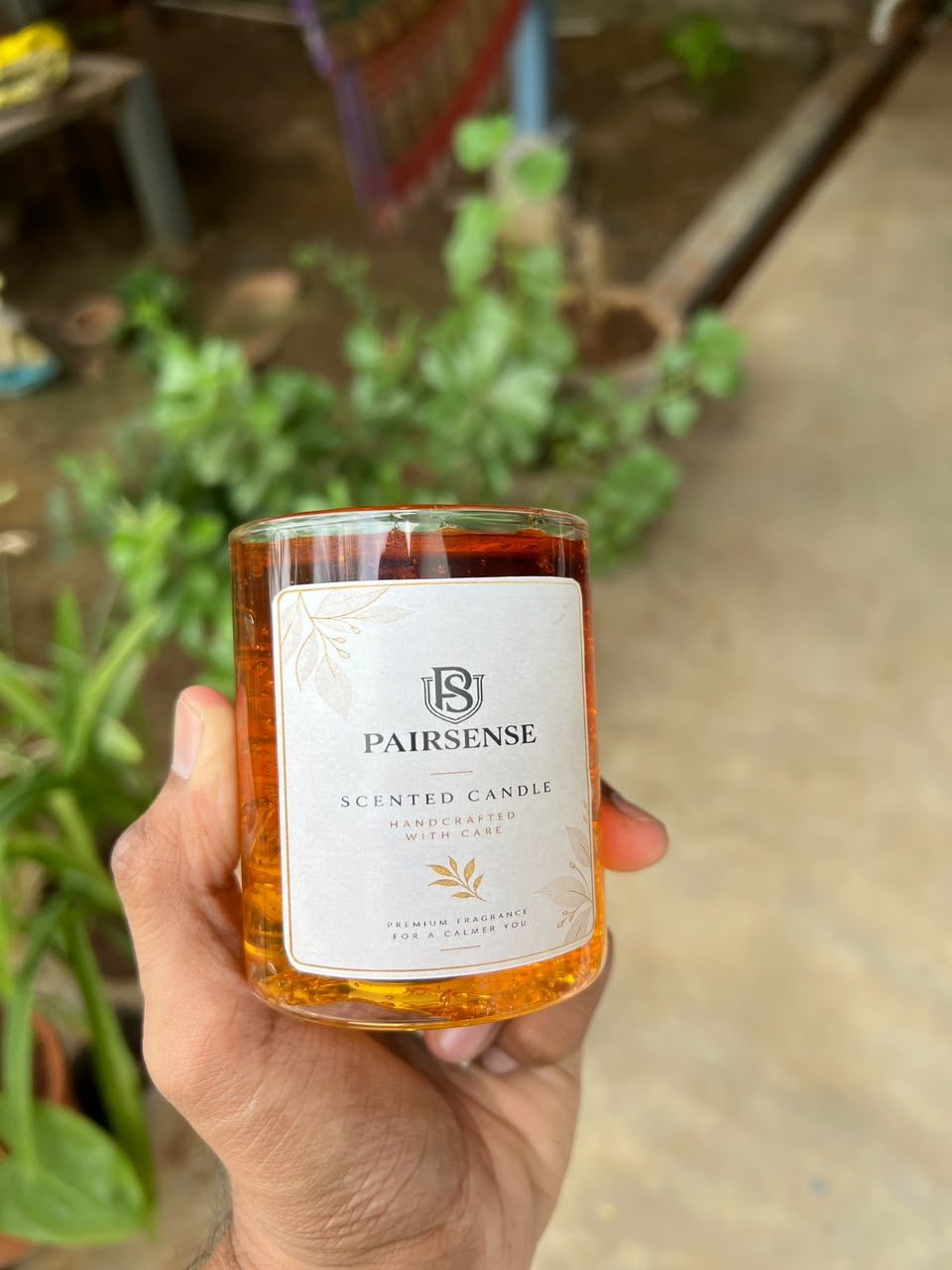 A customer's Pairsense Honey gel candle, lit on a wooden table, held outdoors and glowing