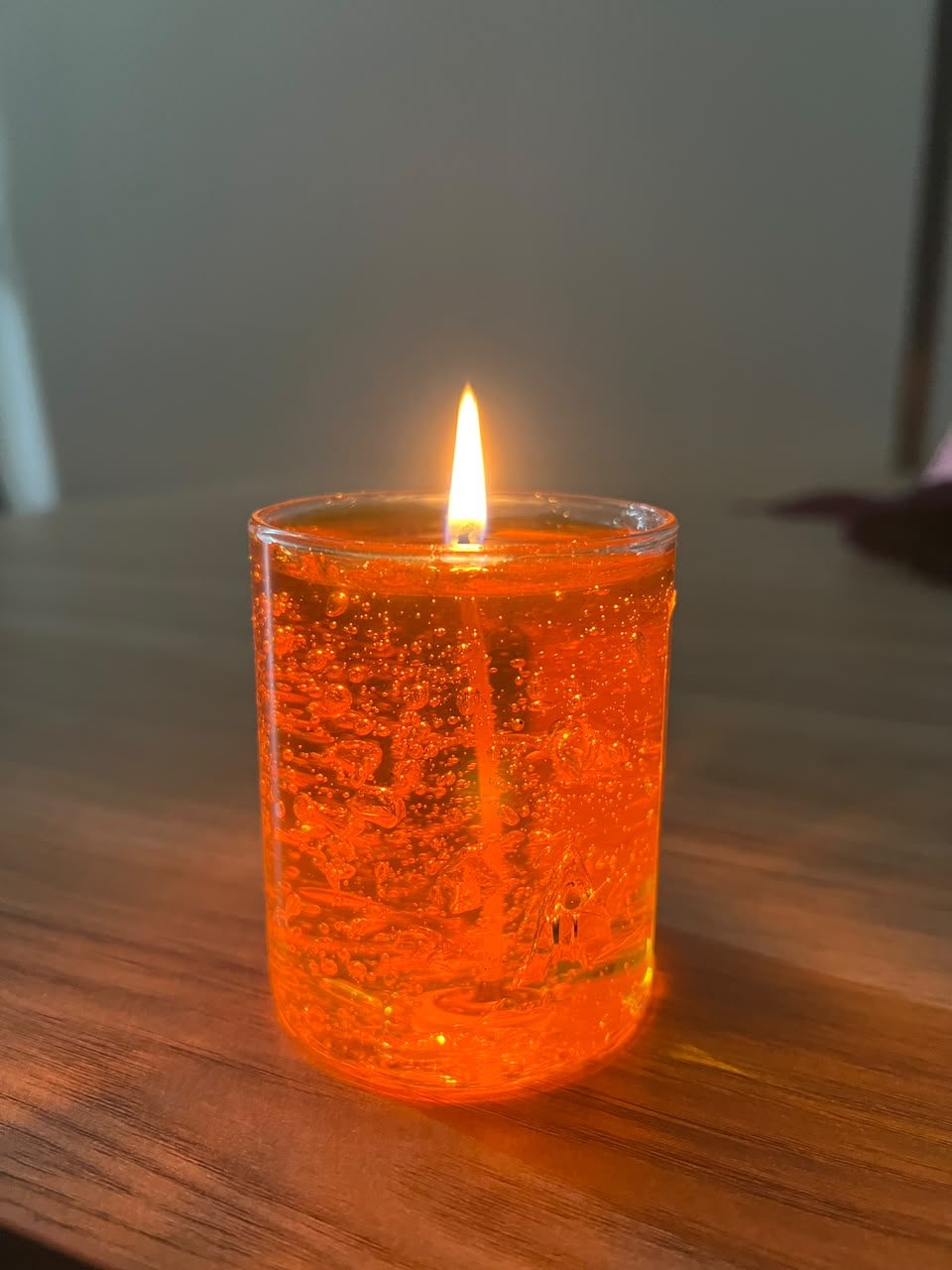 A customer's Pairsense Honey gel candle, lit on a wooden table, held outdoors and glowing
