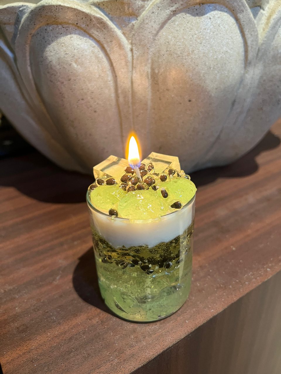 A customer's Pairsense Passion Fruit & Green Grape candle, green gel with passion fruit seeds, lit on a shelf