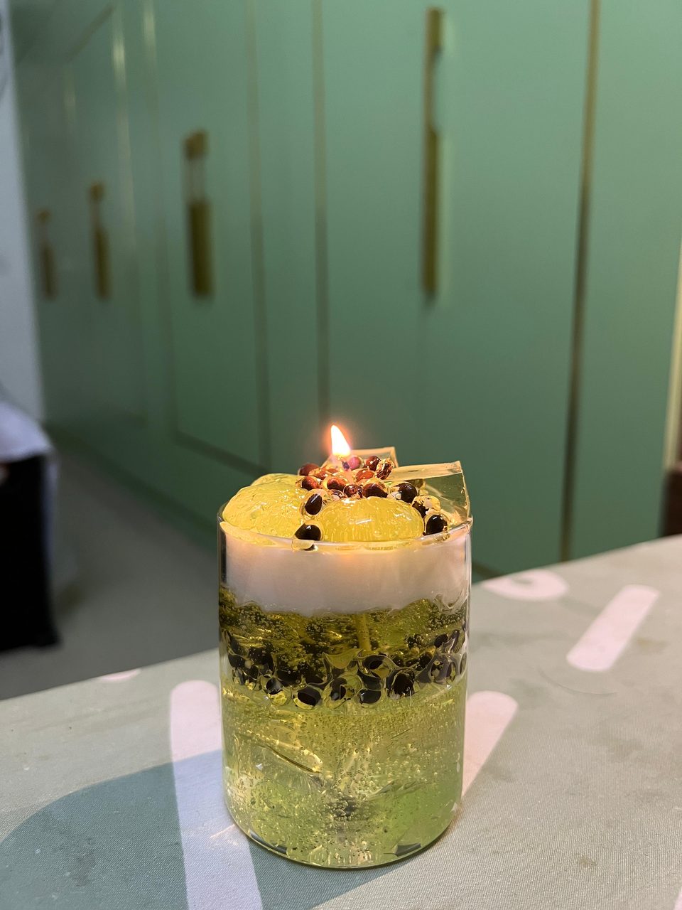 A customer's Pairsense Passion Fruit & Green Grape candle, green gel with passion fruit seeds, lit on a shelf