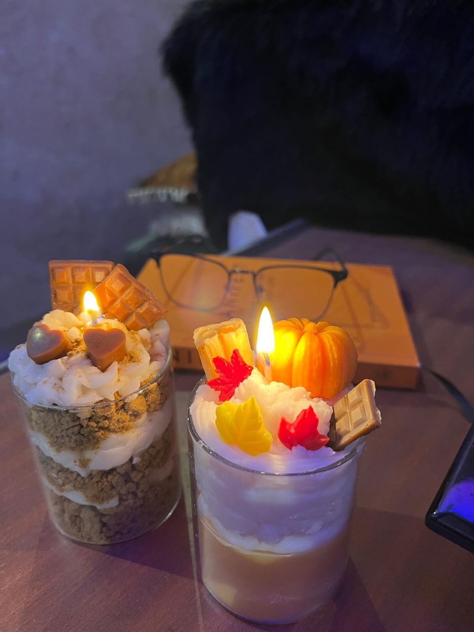 A customer's Pairsense Pumpkin Spice candle, a wax pumpkin and autumn leaves on whipped wax, beside a Chocolate Heart candle