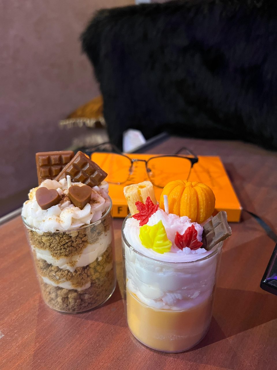 A customer's Pairsense Pumpkin Spice candle, a wax pumpkin and autumn leaves on whipped wax, beside a Chocolate Heart candle