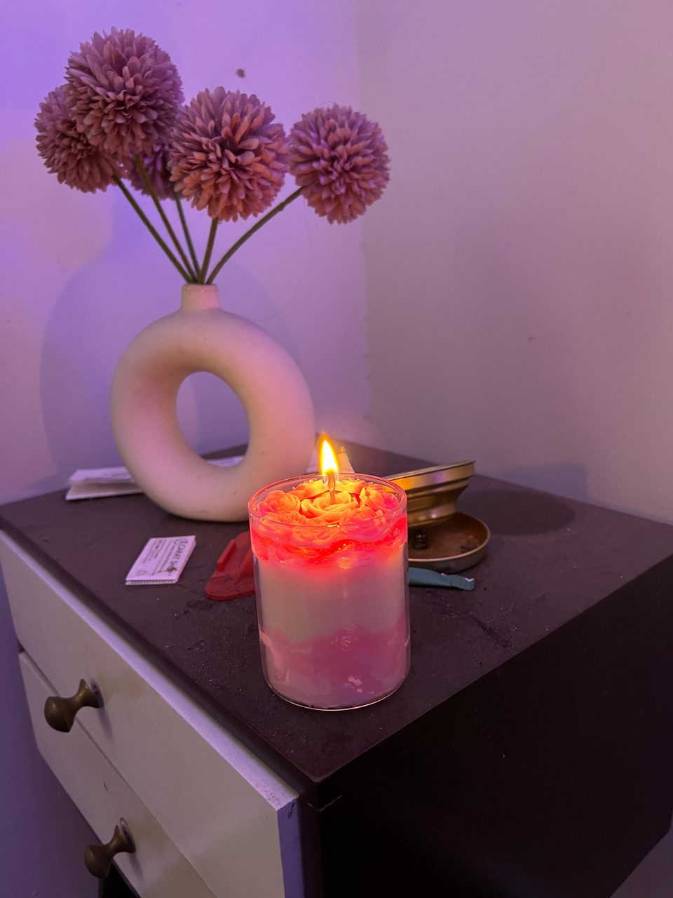 A customer's Pairsense Rose Poudré candle lit on a bedside table, its rose top glowing pink