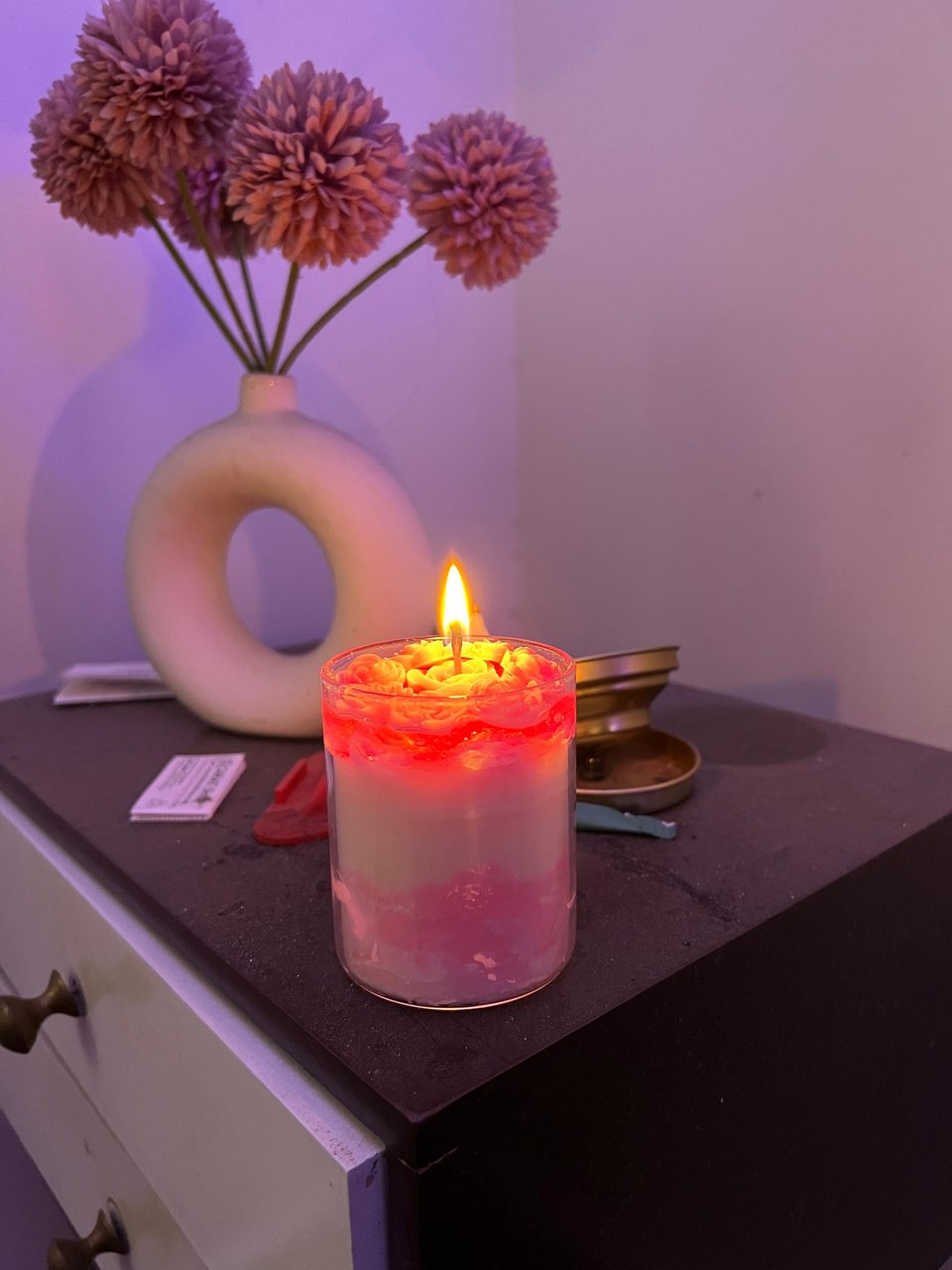 A customer's Pairsense Rose Poudré candle lit on a bedside table, its rose top glowing pink