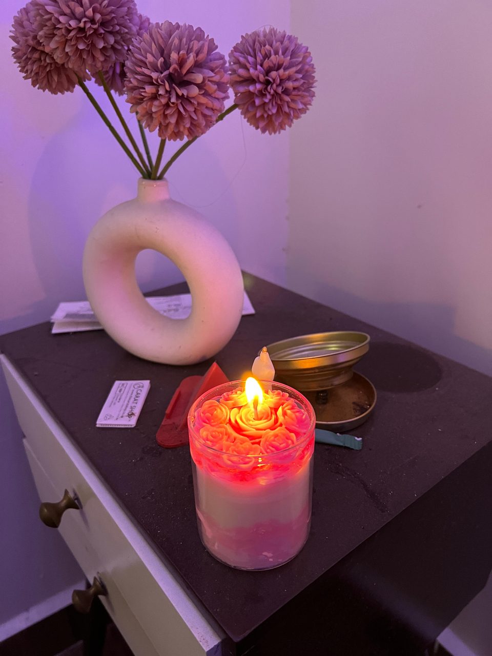 A customer's Pairsense Rose Poudré candle lit on a bedside table, its rose top glowing pink