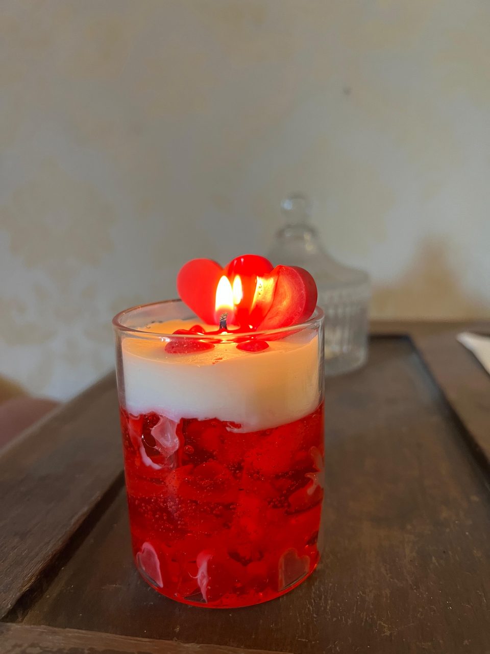 A customer's Pairsense Rouge Amour candle, two red wax hearts over red gel, lit and held in the hand