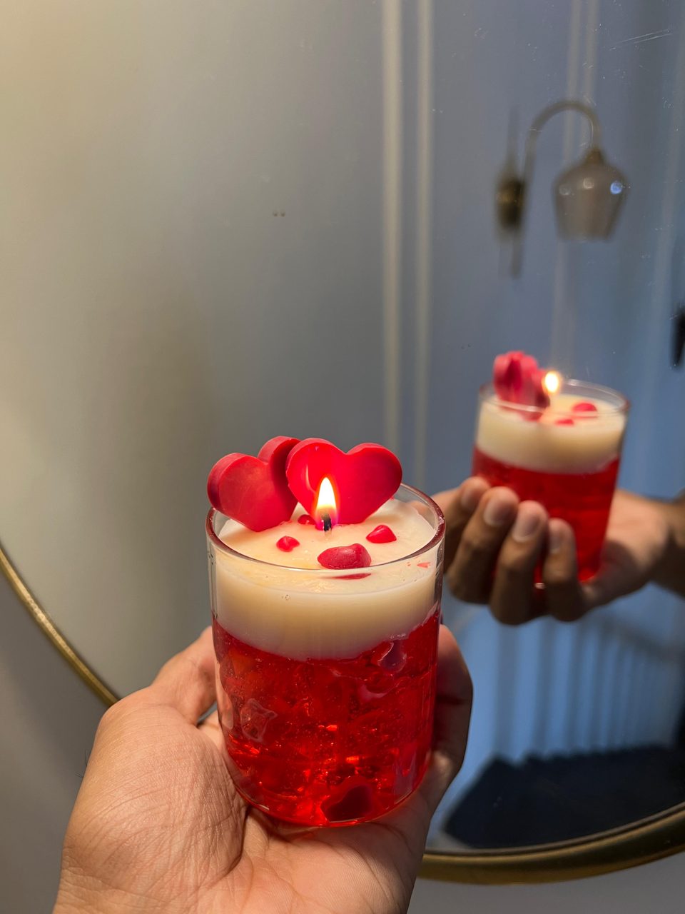 A customer's Pairsense Rouge Amour candle, two red wax hearts over red gel, lit and held in the hand