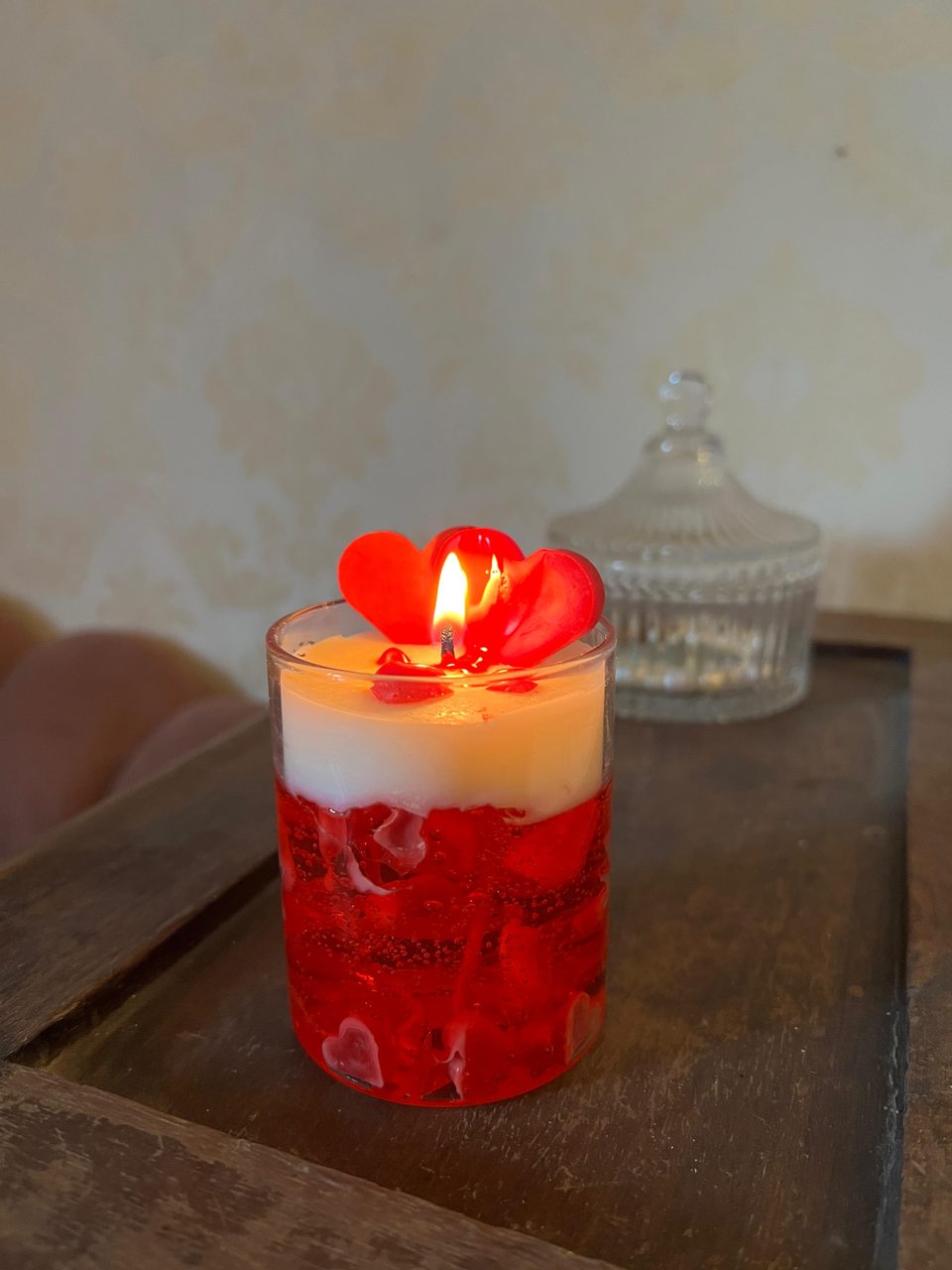 A customer's Pairsense Rouge Amour candle, two red wax hearts over red gel, lit and held in the hand