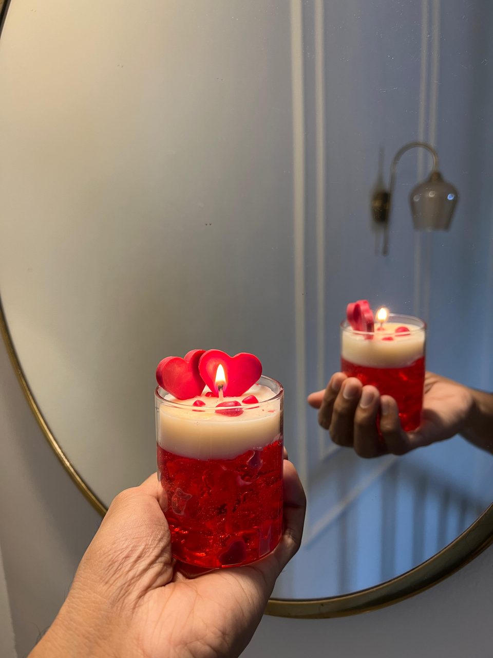 A customer's Pairsense Rouge Amour candle, two red wax hearts over red gel, lit and held in the hand